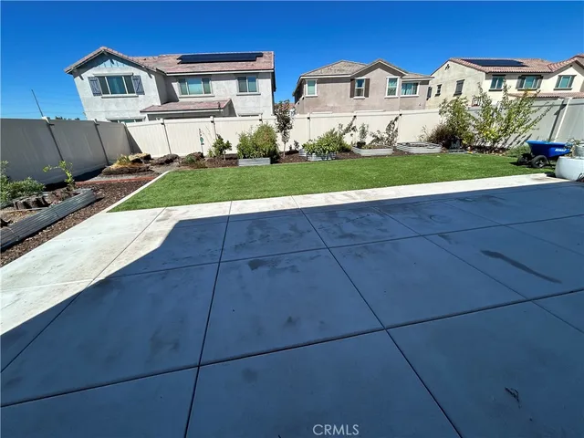 a view of a white house with a yard and table and chairs under an umbrella