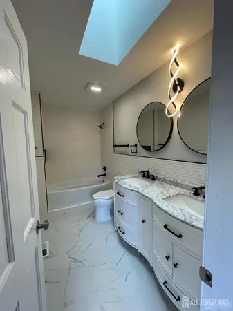 a bathroom with a granite countertop sink mirror toilet and vanity