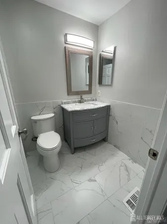 a bathroom with a granite countertop toilet sink and mirror