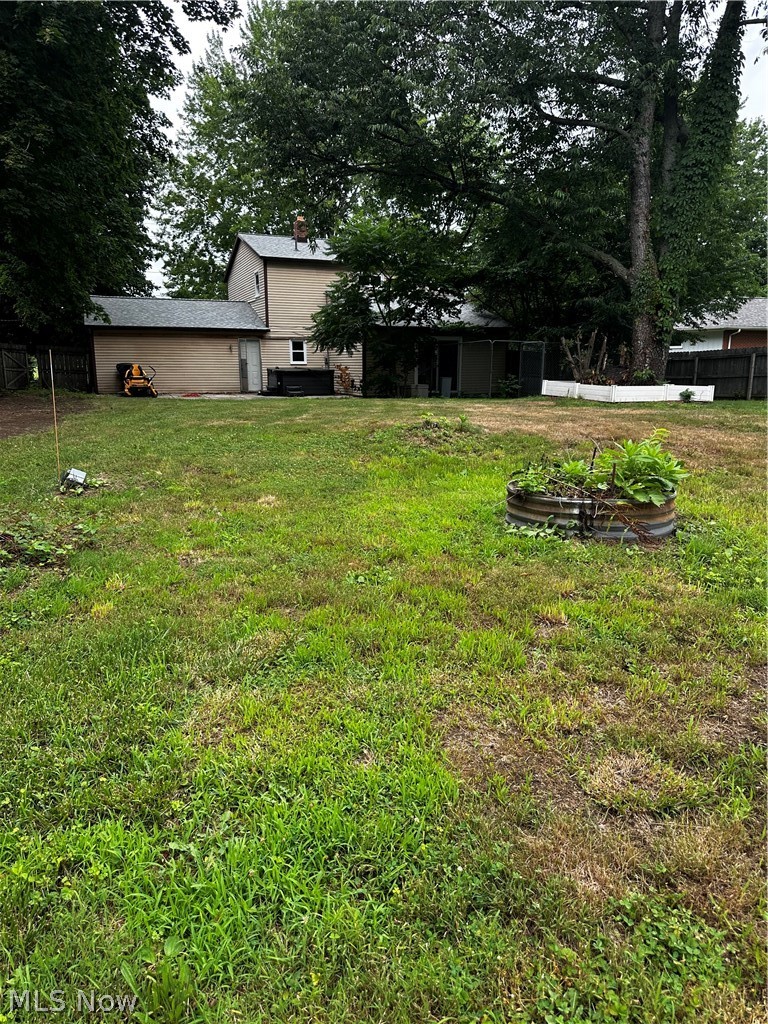 198 Park Road Painesville, OH 44077 - Photo 29 of 31 Spacious rear yard with mature trees and a two-story residence featuring a ground-level patio and a screened-in porch