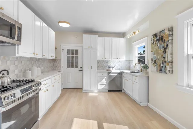 a kitchen with granite countertop a stove a sink dishwasher and a refrigerator with white cabinets