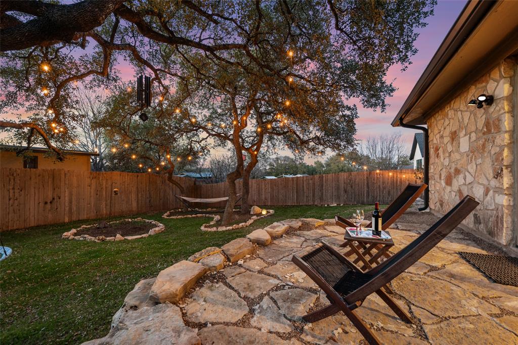 2210 Red Fox Road Austin, TX 78734 - Photo 35 of 40 A flagstone patio and lush green lawn create an inviting backyard retreat, perfect for evening relaxation under string lights.