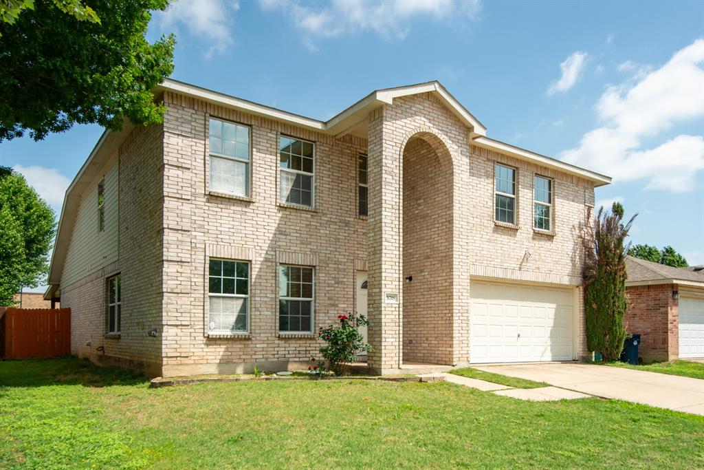 5718 Green Ivy Road Denton, TX 76210 - Photo 31 of 37 Two-story brick facade residence featuring an arched entryway, multiple windows on both levels, and an integrated two-car garage with a white door