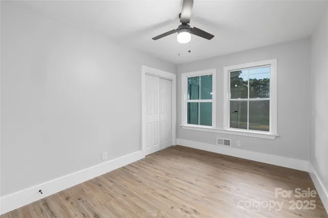 an empty room with wooden floor and windows