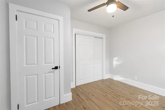 an empty room with wooden floor closet and windows