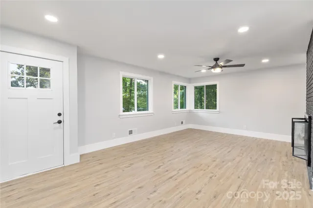 an empty room with wooden floor and windows