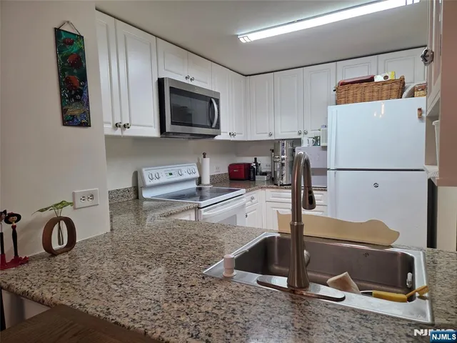a kitchen with kitchen island granite countertop a sink a stove and a refrigerator