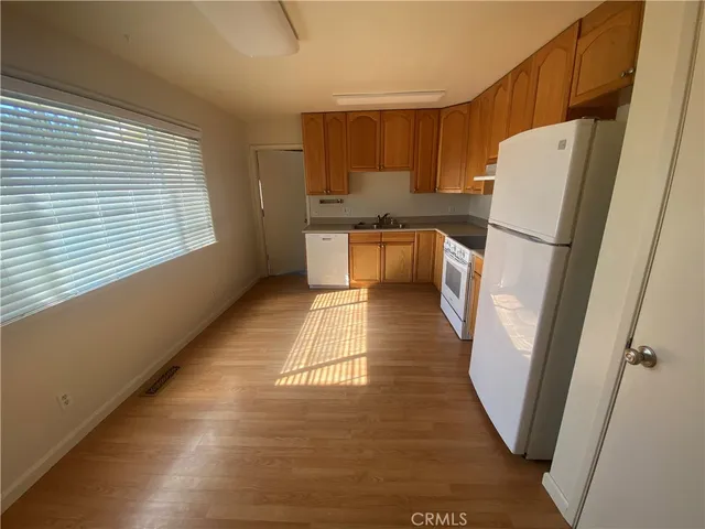 a kitchen with a refrigerator a stove top oven and wooden floor