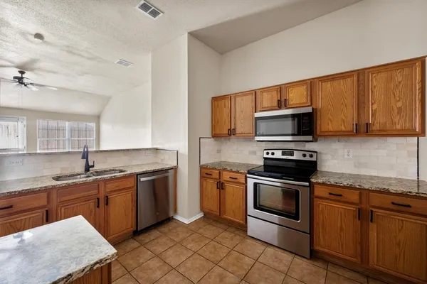 a kitchen with stainless steel appliances granite countertop a sink dishwasher stove top oven and microwave
