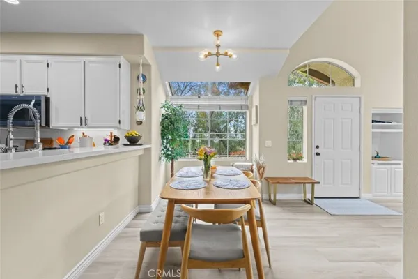 a dining room with wooden floor a chandelier a wooden table and chairs