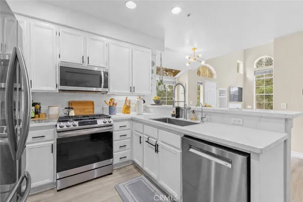 a kitchen with stainless steel appliances granite countertop a stove a sink and a microwave