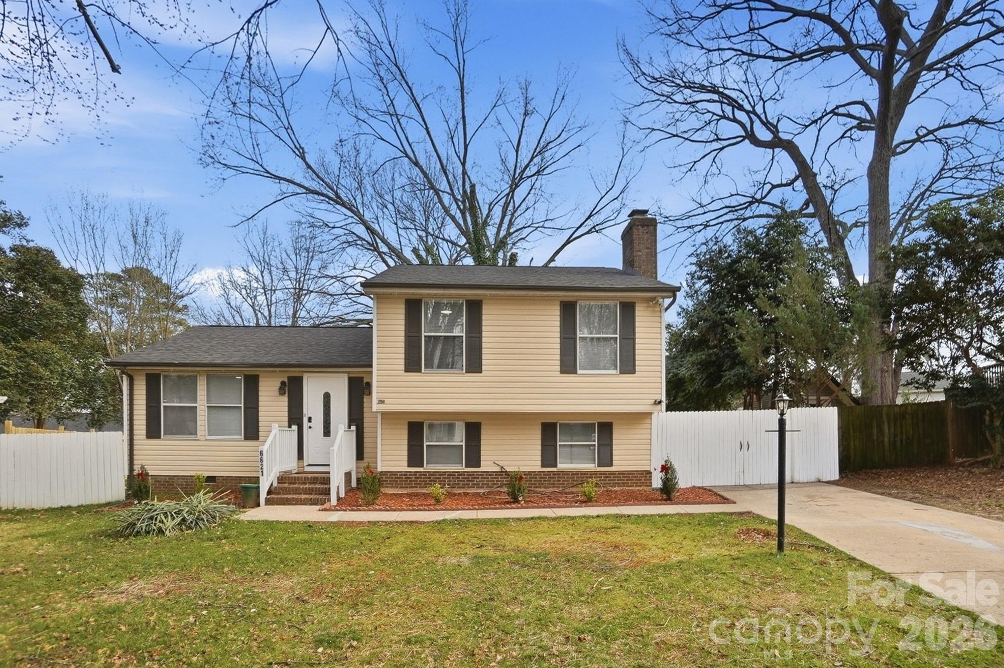 a white house with a large tree and a yard in front of it