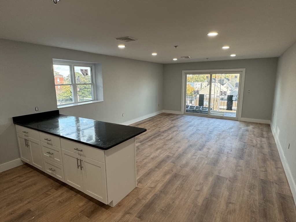 220 Broadway, Unit 2 Revere, MA 02151 - Photo 2 of 10 a kitchen with granite countertop white cabinets and wooden floor