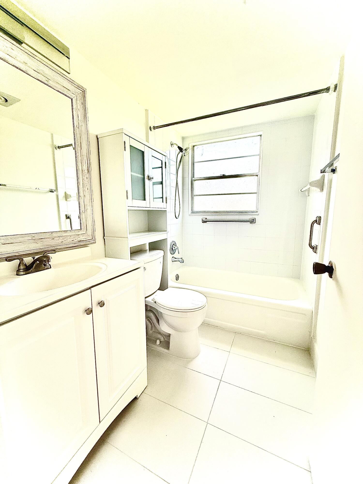 402 Brighton J, Unit J Boca Raton, FL 33434 - Photo 17 of 21 a bathroom with a sink a toilet and shower