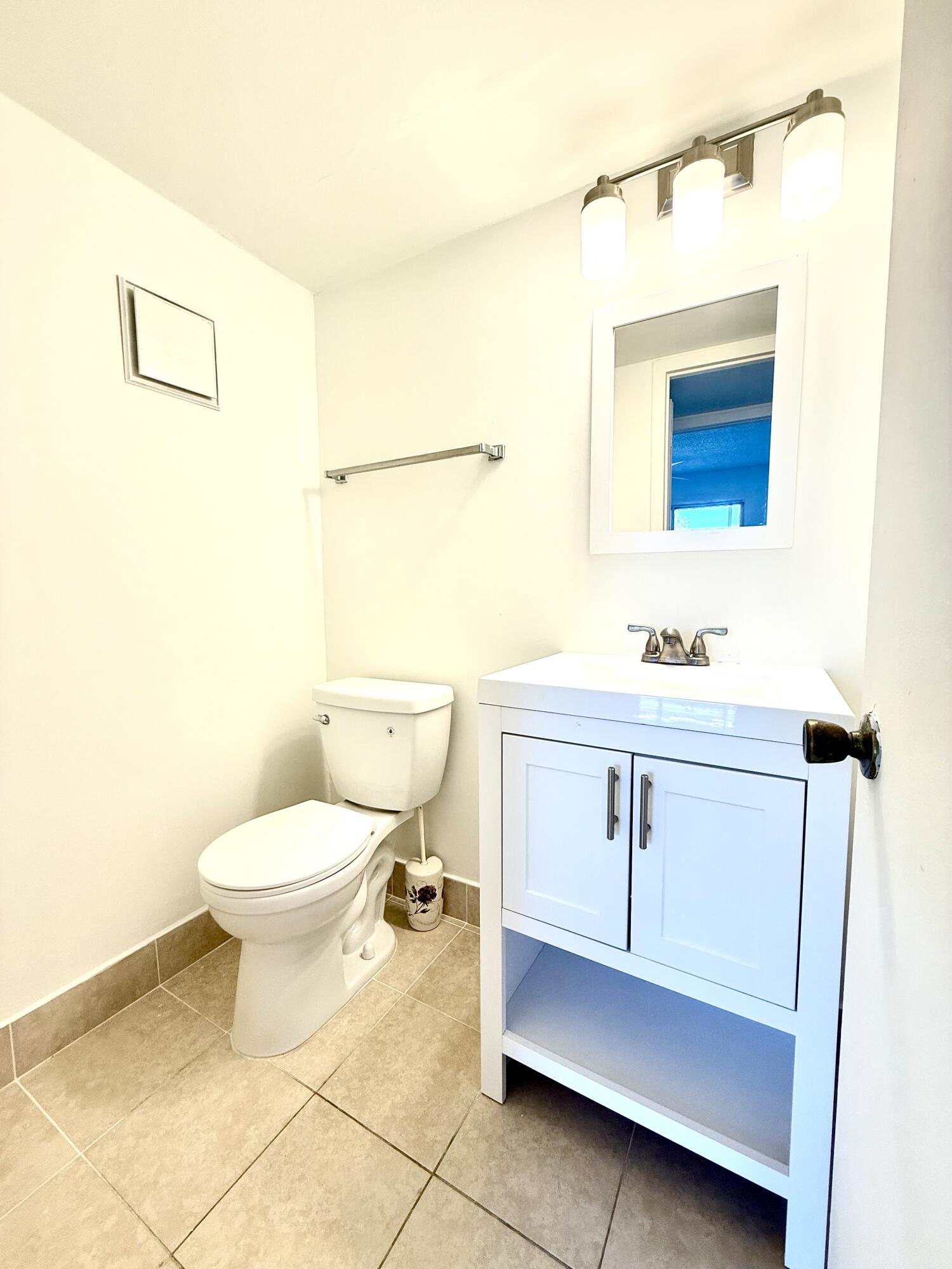 402 Brighton J, Unit J Boca Raton, FL 33434 - Photo 18 of 21 a bathroom with a sink a toilet and mirror