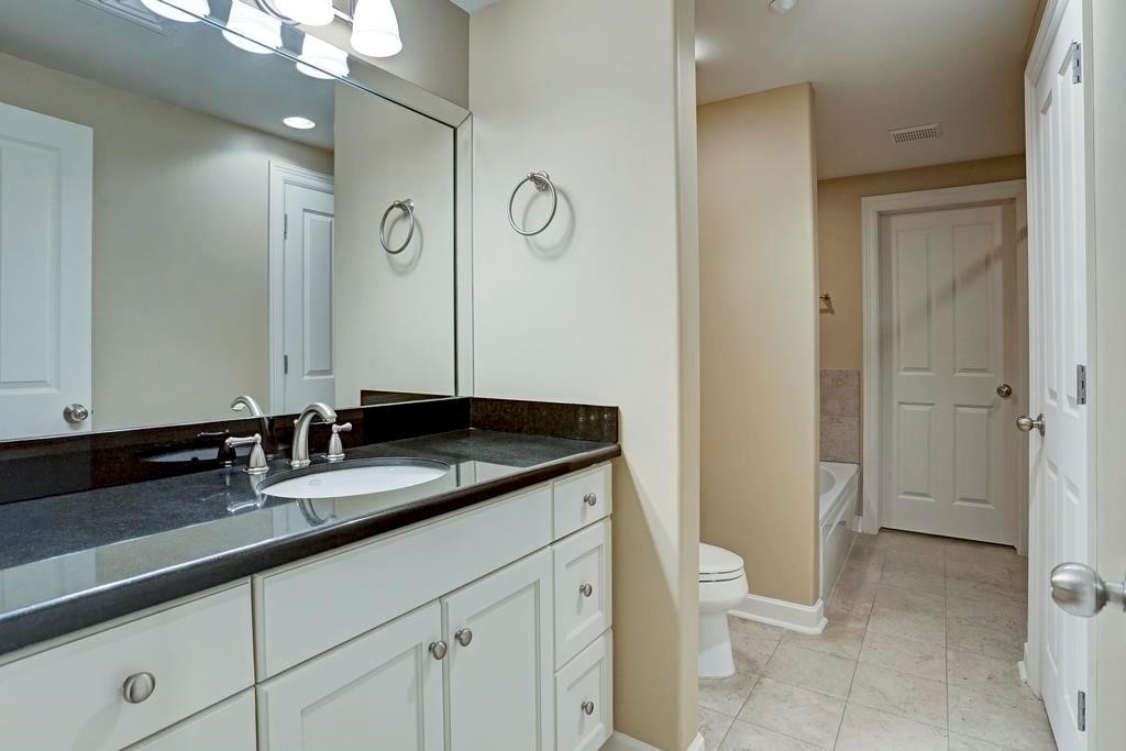 914 Main Street, Unit 1107 Houston, TX 77002 - Photo 4 of 14 a bathroom with a granite countertop sink a toilet and a large mirror