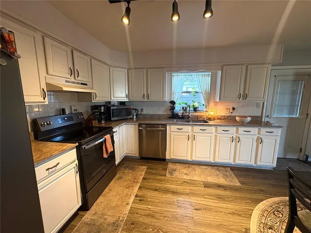 a kitchen with granite countertop white cabinets sink and stainless steel appliances