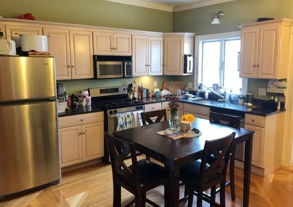 a kitchen with refrigerator a stove a dining table and chairs