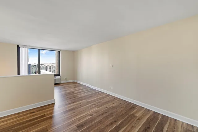a view of an empty room with wooden floor and a window