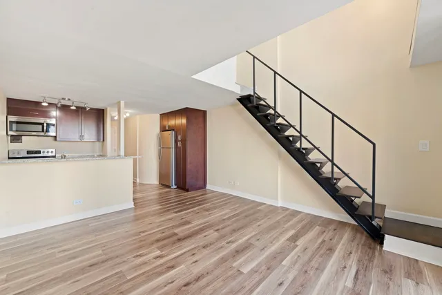 a view of an empty room with wooden floor and stairs