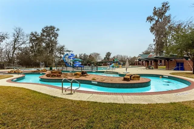 a view of swimming pool with lawn chairs and iron fence