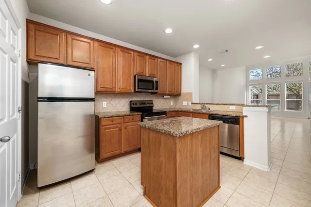 a kitchen with stainless steel appliances granite countertop a refrigerator stove microwave and sink