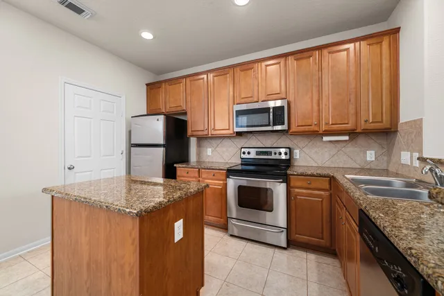 a kitchen with granite countertop a sink stove and refrigerator