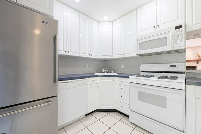 a kitchen with granite countertop white cabinets and white appliances