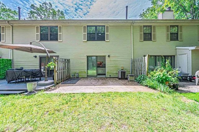 a backyard of a house with table and chairs plants and large trees