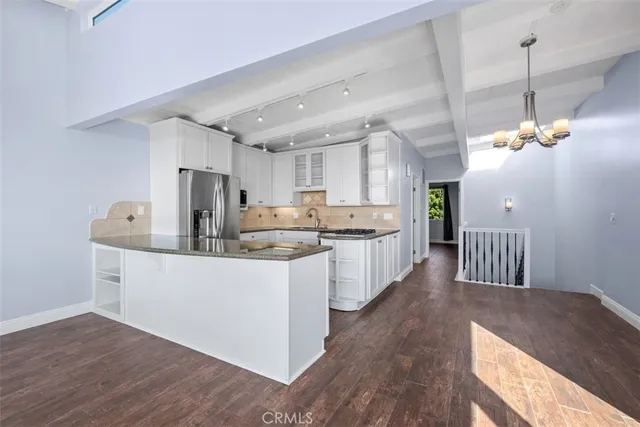 a large kitchen with kitchen island a island a sink a center island stainless steel appliances and a chandelier
