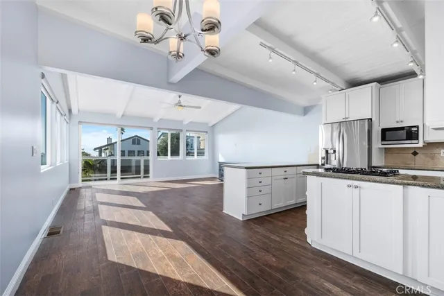 a kitchen with stainless steel appliances granite countertop a stove a refrigerator a sink dishwasher and white cabinets with wooden floor