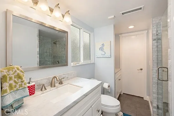 a bathroom with a granite countertop sink vanity mirror and toilet
