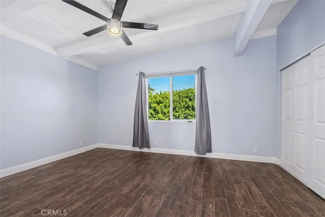 an empty room with wooden floor and a ceiling fan