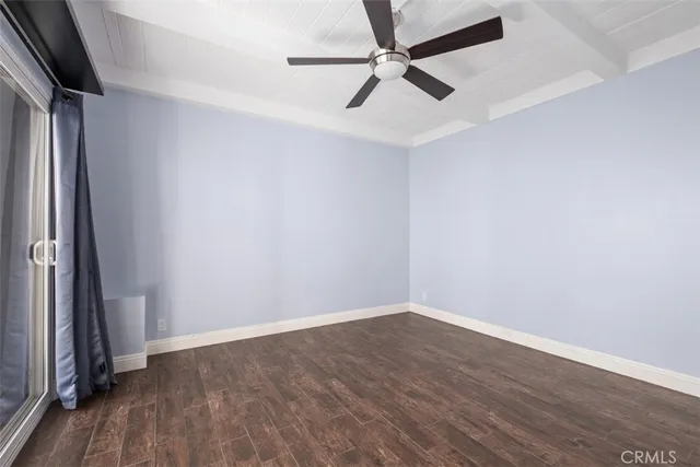 an empty room with wooden floor and fan
