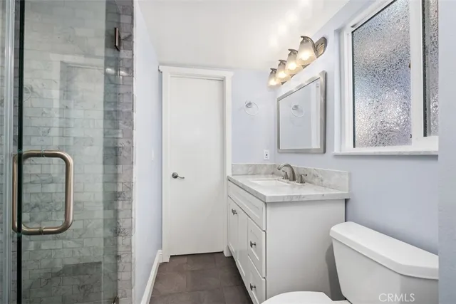 a bathroom with a granite countertop toilet sink and mirror