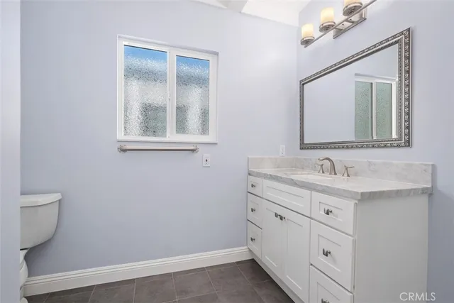 a bathroom with a granite countertop sink mirror and a toilet