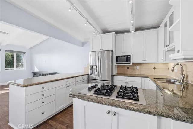 a kitchen with granite countertop a sink stove and refrigerator