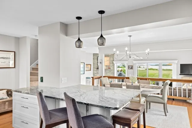 a dining room with wooden floor a chandelier a wooden table and chairs