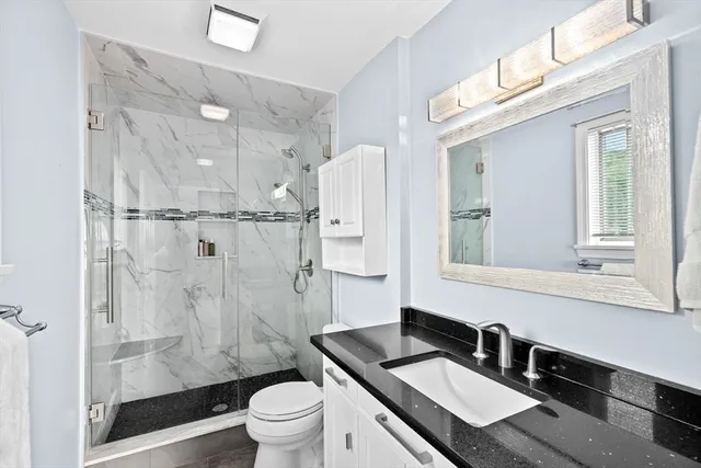 a bathroom with a granite countertop sink toilet a mirror a vanity and shower