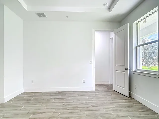 a view of an empty room with wooden floor and a window