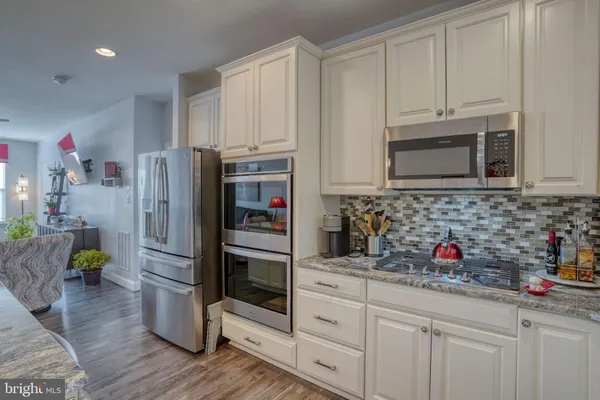 a kitchen with stainless steel appliances kitchen island granite countertop a refrigerator a stove top oven a sink with island and chairs