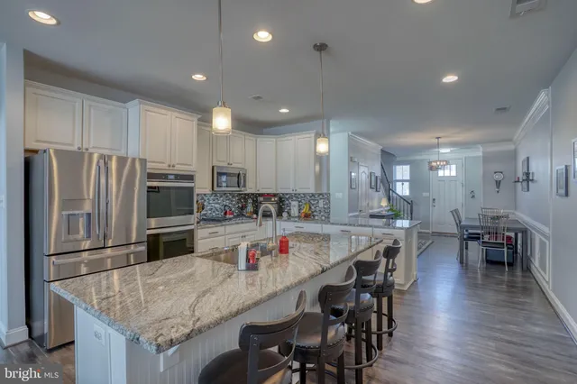 a kitchen with stainless steel appliances granite countertop a table chairs sink refrigerator and microwave