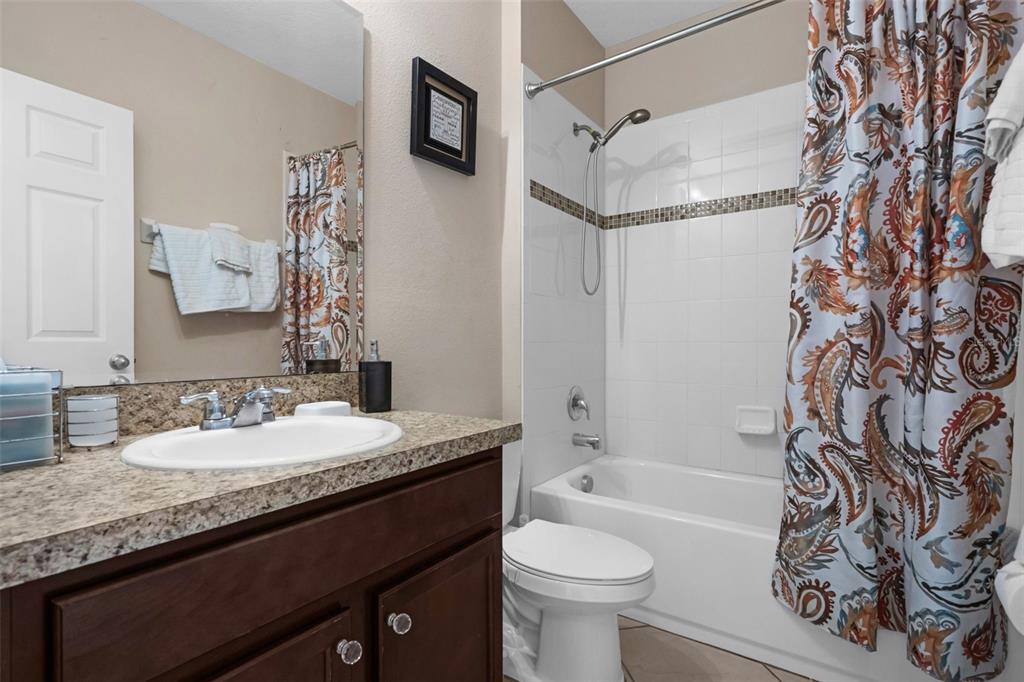 540 Vitoria Road Davenport, FL 33837 - Photo 18 of 21 a bathroom with a granite countertop sink toilet a mirror a bathtub and shower