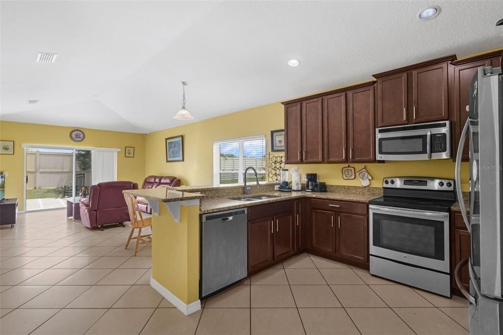 540 Vitoria Road Davenport, FL 33837 - Photo 10 of 21 a kitchen with stainless steel appliances granite countertop a stove microwave and cabinets