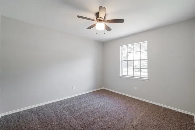 an empty room with a window and a ceiling fan