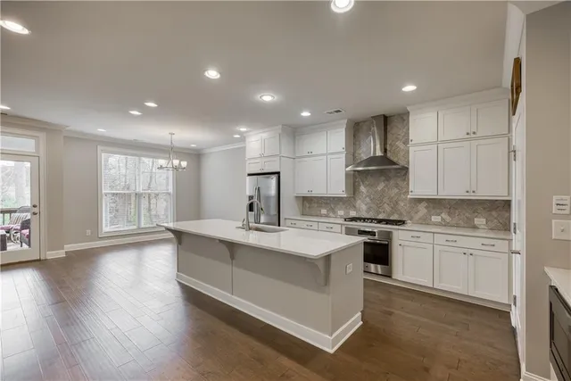 a large kitchen with stainless steel appliances granite countertop a stove a sink dishwasher and a white countertops with wooden floor