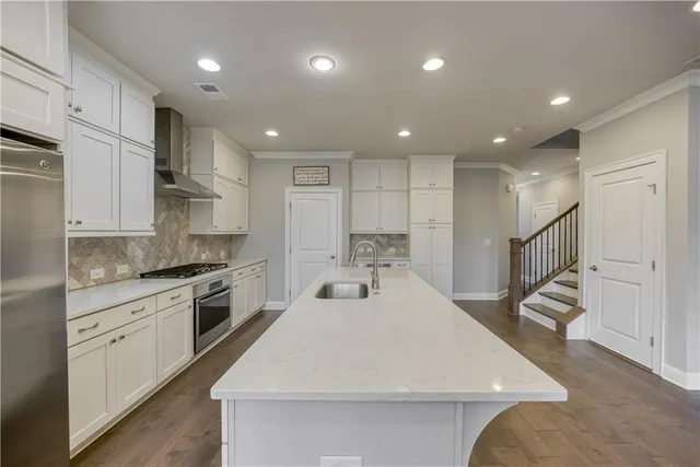 a kitchen with stainless steel appliances kitchen island granite countertop a sink a stove a refrigerator and cabinets