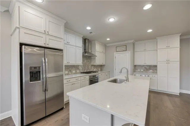 a kitchen with refrigerator a stove and white cabinets with wooden floor