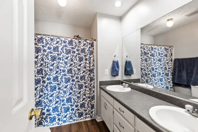 a bathroom with a granite countertop double vanity sink mirror and shower
