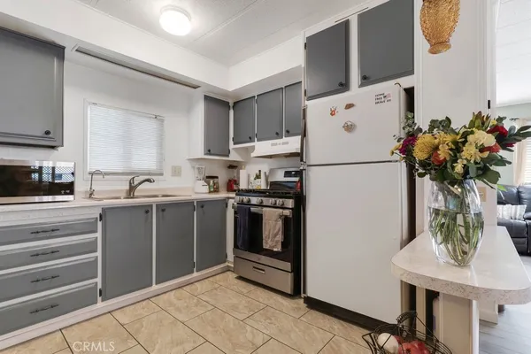 a kitchen with stainless steel appliances a refrigerator sink cabinets dining table and chairs